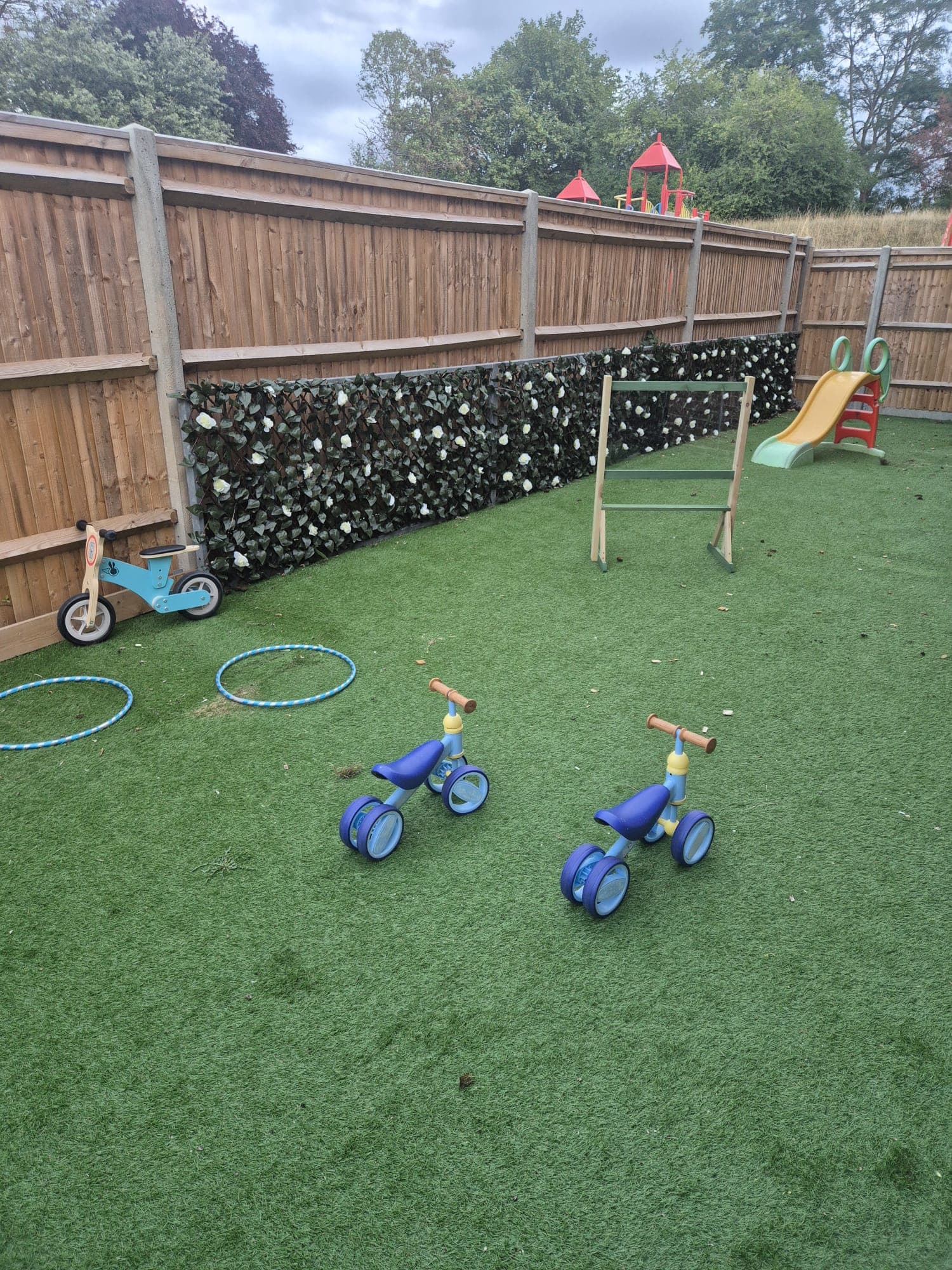 Trikes, hoops and a slide ready for outdoor play at Daisy Rose Daycare.